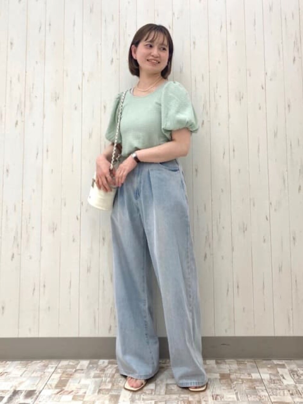 グリーン系のTシャツ/カットソー、ブルー系のデニムパンツ、ホワイト系のショルダーバッグを着用したレディースの夏コーディネートの2枚目の写真