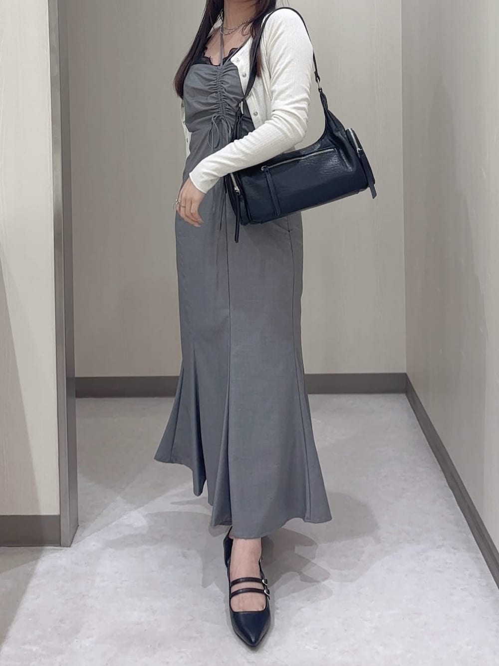 グレー系のワンピース、ブラック系のカーディガン/ボレロ、ブラック系のパンプスを着用したレディースの夏コーディネートの2枚目の写真