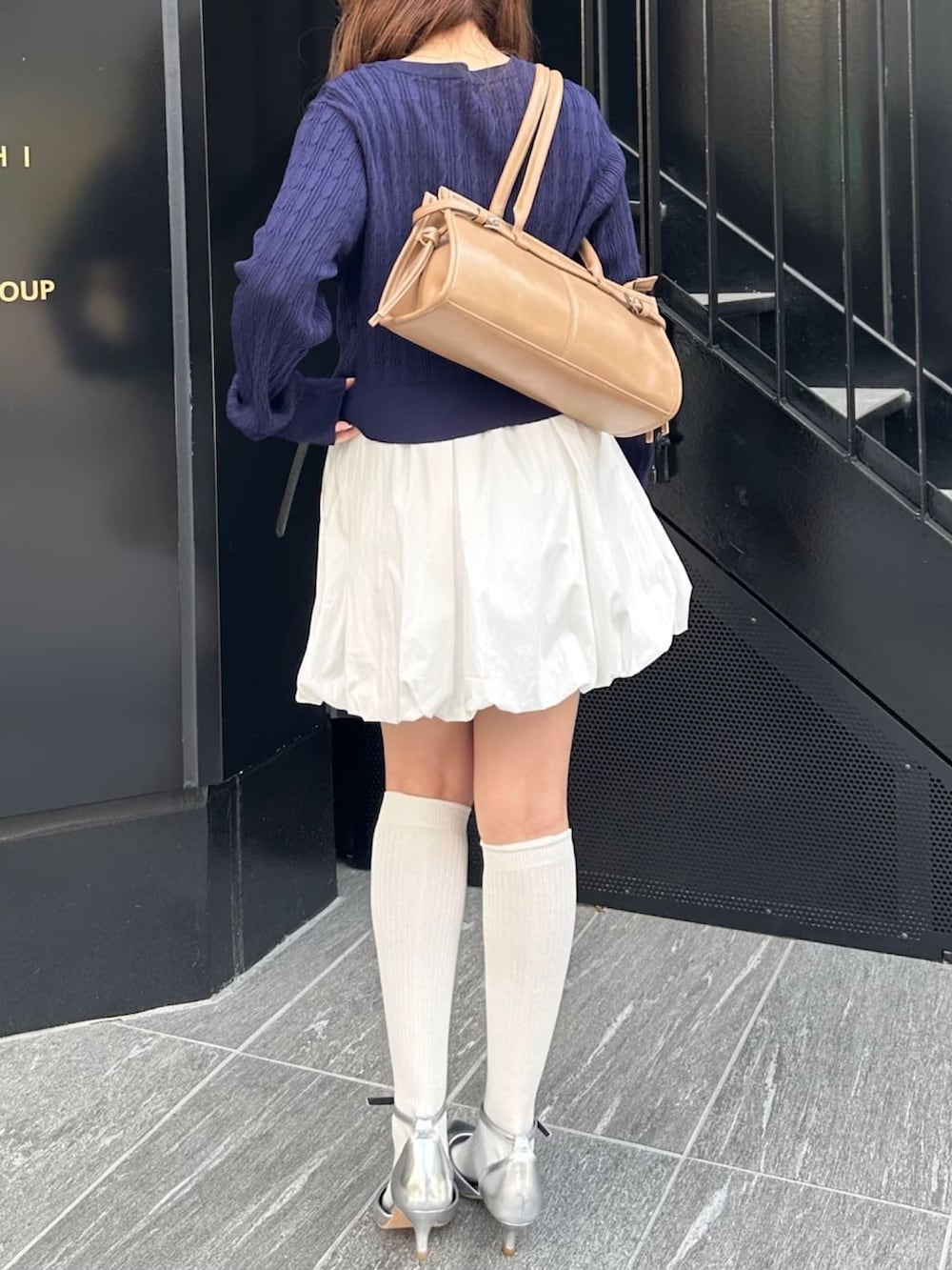 ブルー系のカーディガン/ボレロ、ホワイト系のスカート、ベージュ系のハンドバッグを着用したレディースの春コーディネートの3枚目の写真