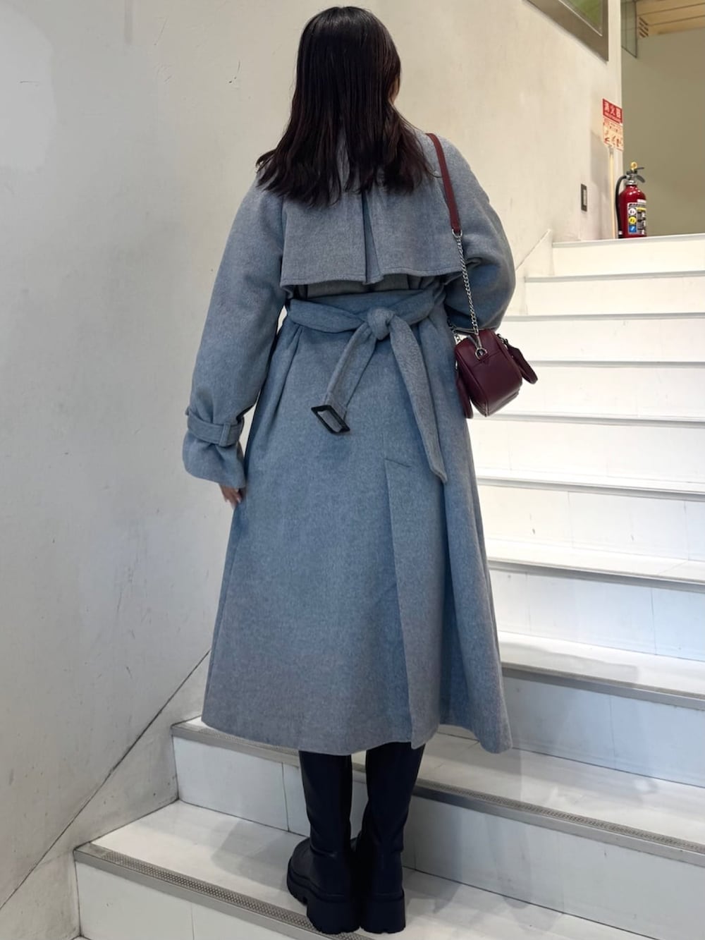 グレー系のトレンチコート、レッド系のショルダーバッグを着用したレディースの秋コーディネートの3枚目の写真