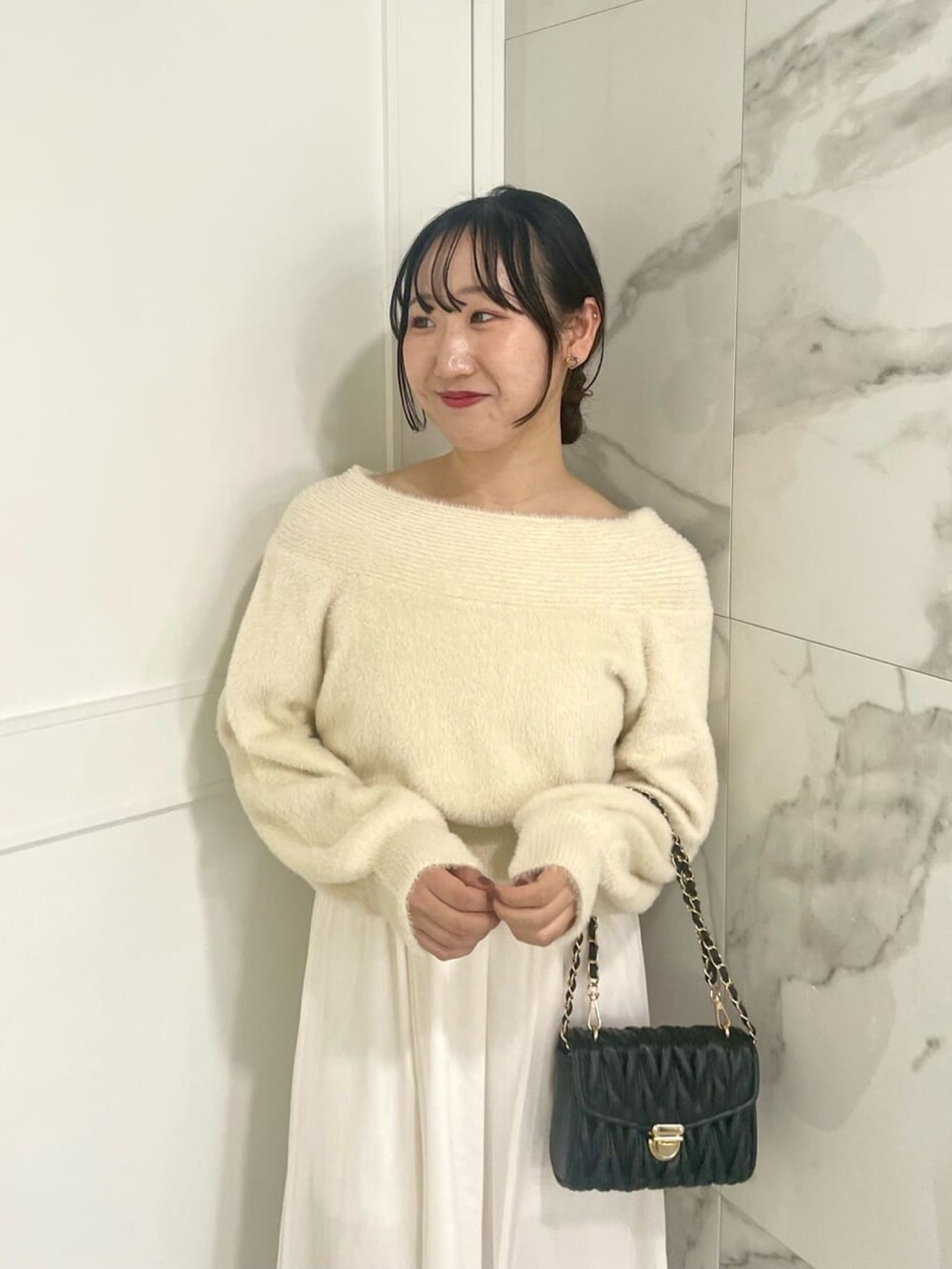 ホワイト系のワンピース、ブラック系のショルダーバッグを着用したレディースの冬コーディネートの2枚目の写真