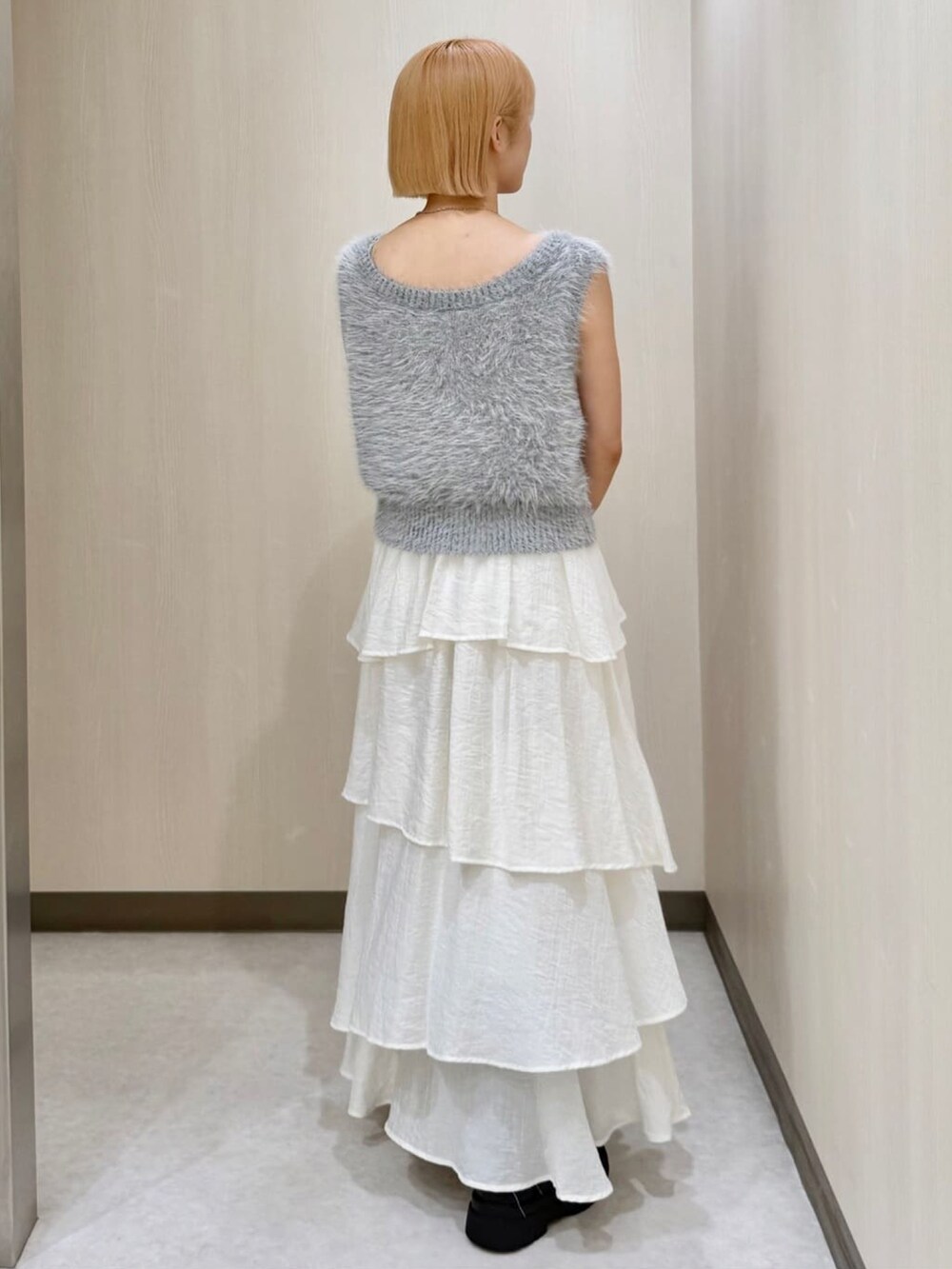 グレー系のベスト、ホワイト系のスカート、ベージュ系のショルダーバッグを着用したレディースの秋コーディネートの3枚目の写真