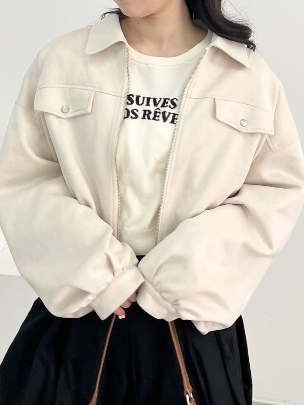 ホワイト系のブルゾン、ホワイト系のニット/セーター、ブラック系のスカートを着用したレディースの春コーディネートの3枚目の写真