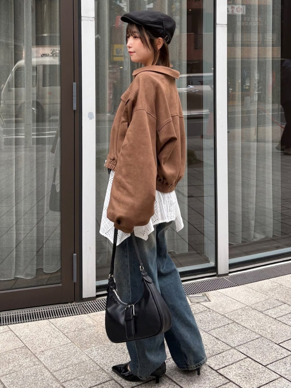 ブラウン系のブルゾン、ホワイト系のワンピース、ブルー系のデニムパンツを着用したレディースの春コーディネートの3枚目の写真