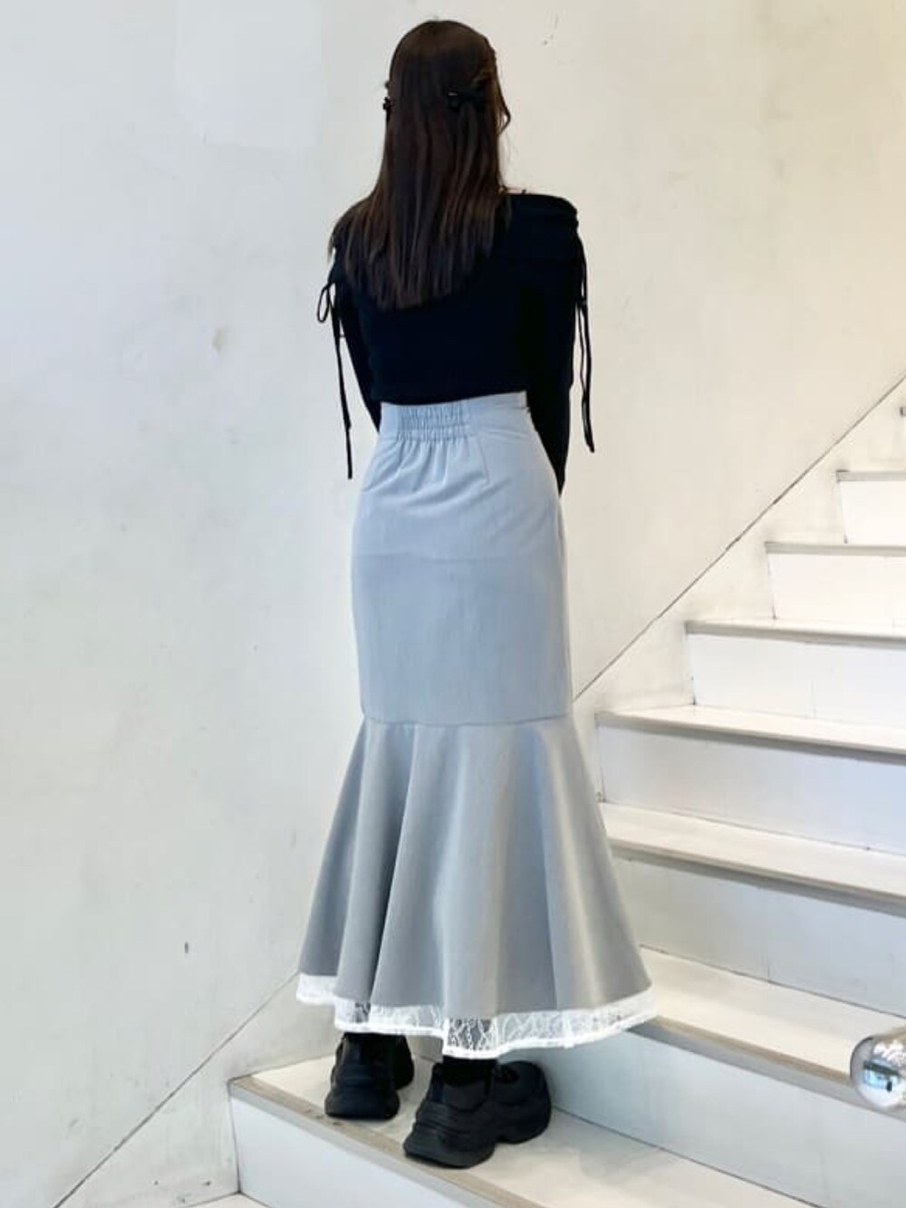 ブラック系のニット/セーター、グレー系のスカート、ホワイト系のショルダーバッグを着用したレディースの冬コーディネートの2枚目の写真