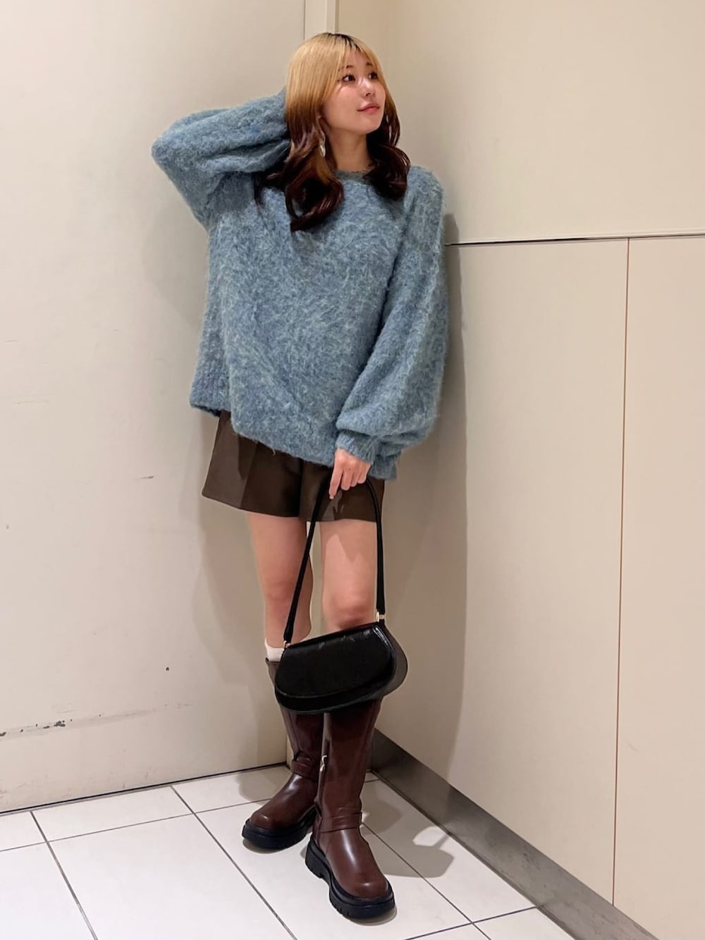 レッド系のニット/セーター、ブラック系のその他パンツ、ブラウン系のブーツを着用したレディースの冬コーディネートの2枚目の写真