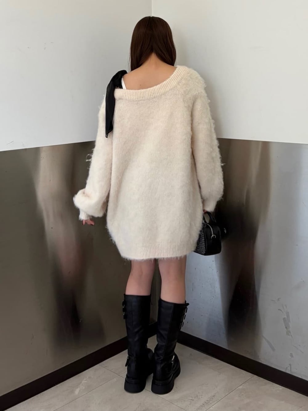 ホワイト系のチュニック、ブラック系のショルダーバッグ、ブラック系のブーツを着用したレディースの冬コーディネートの3枚目の写真