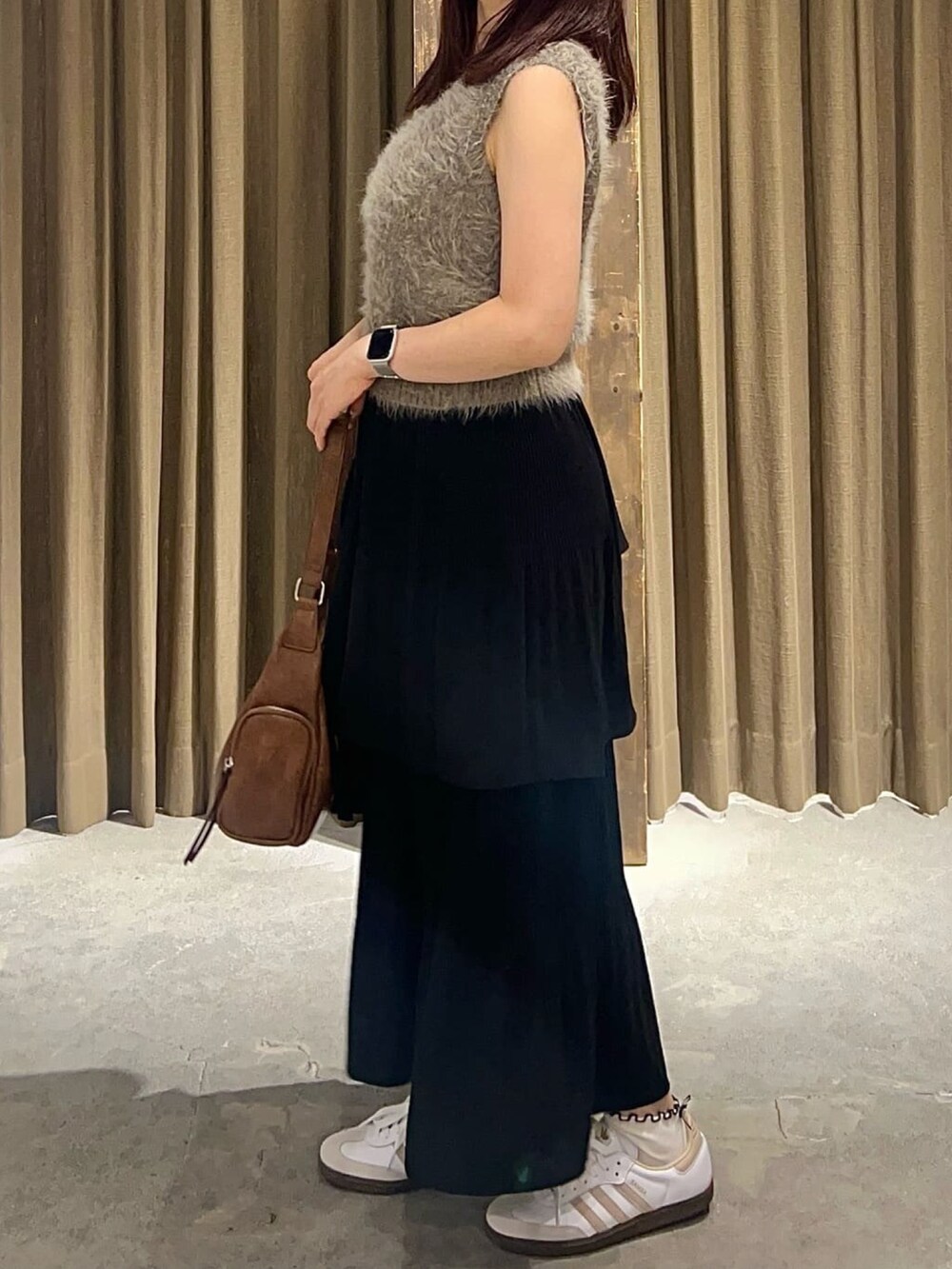 ブラウン系のベスト、ブラック系のスカート、ブラウン系のハンドバッグを着用したレディースの秋コーディネートの3枚目の写真