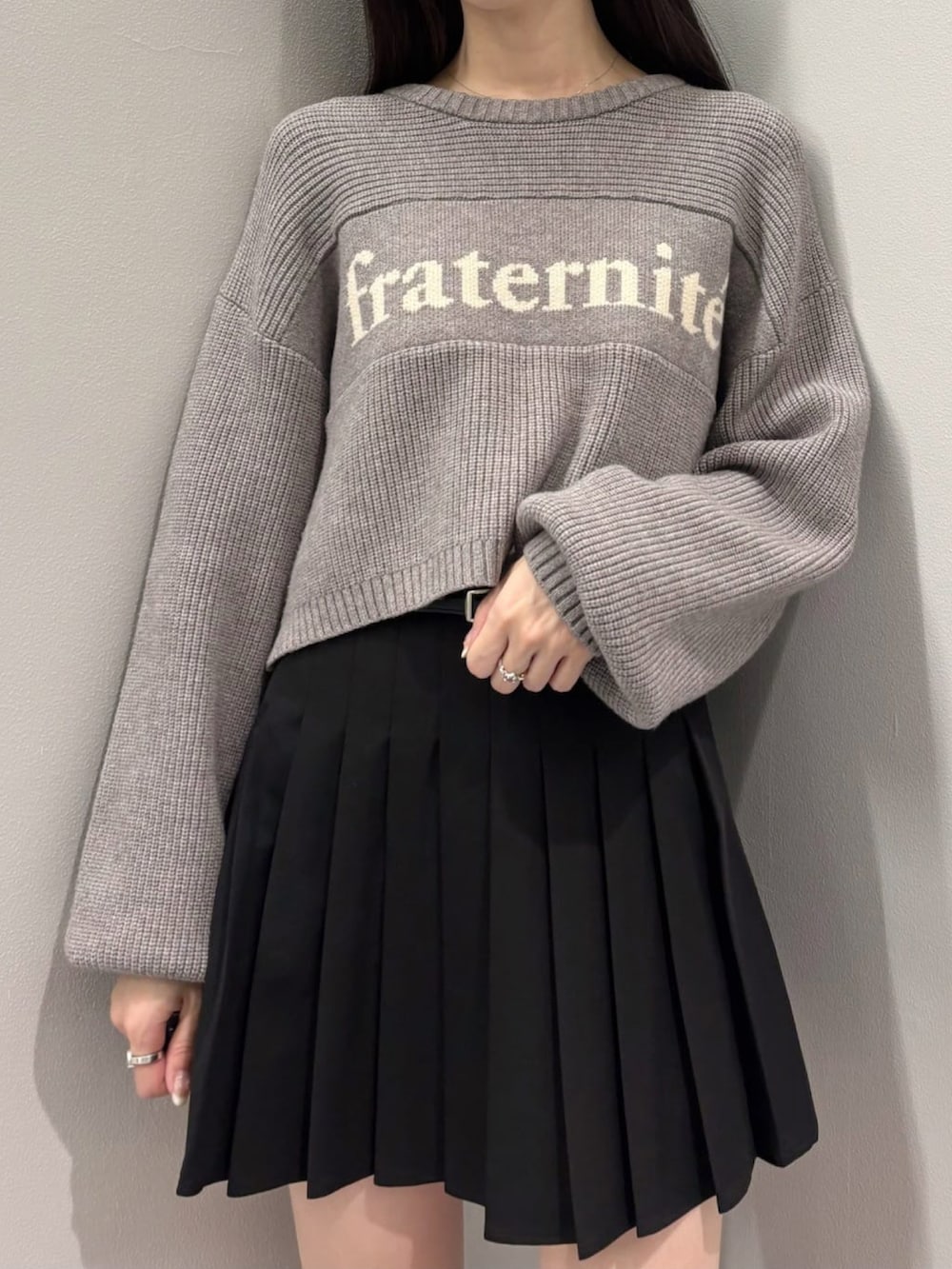 グレー系のニット/セーター、ブラック系のスカート、ブラック系のブーツを着用したレディースの冬コーディネートの2枚目の写真