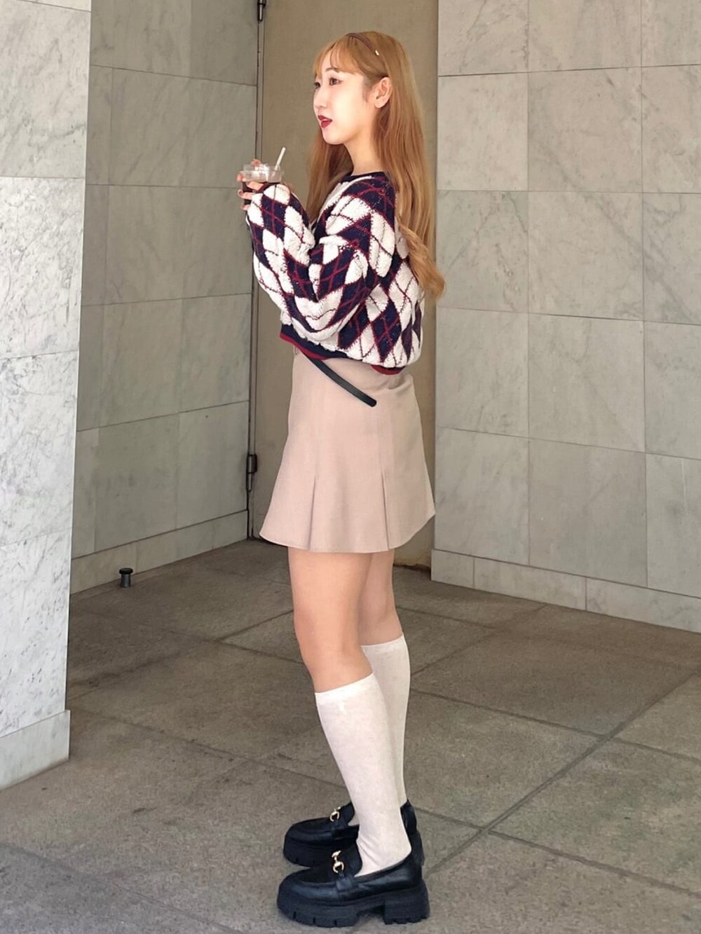 ブルー系のニット/セーター、ベージュ系のスカート、グレー系のローファーを着用したレディースの冬コーディネートの2枚目の写真