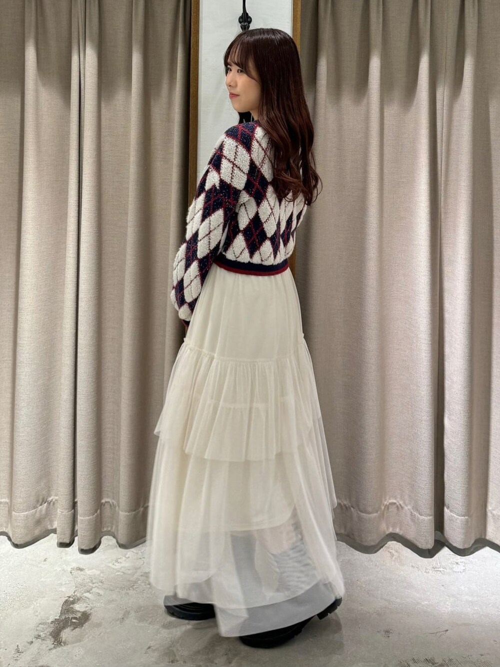 ブルー系のニット/セーター、ブラック系のボストンバッグ、ホワイト系のスカートを着用したレディースの冬コーディネートの2枚目の写真