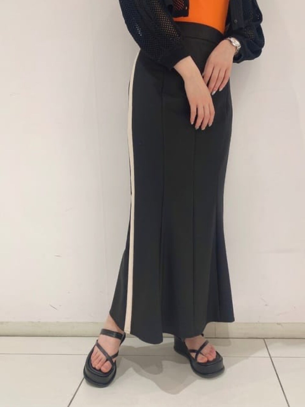 ブラック系のカーディガン/ボレロ、オレンジ系のタンクトップ、ブラック系のスカートを着用したレディースの夏コーディネートの2枚目の写真