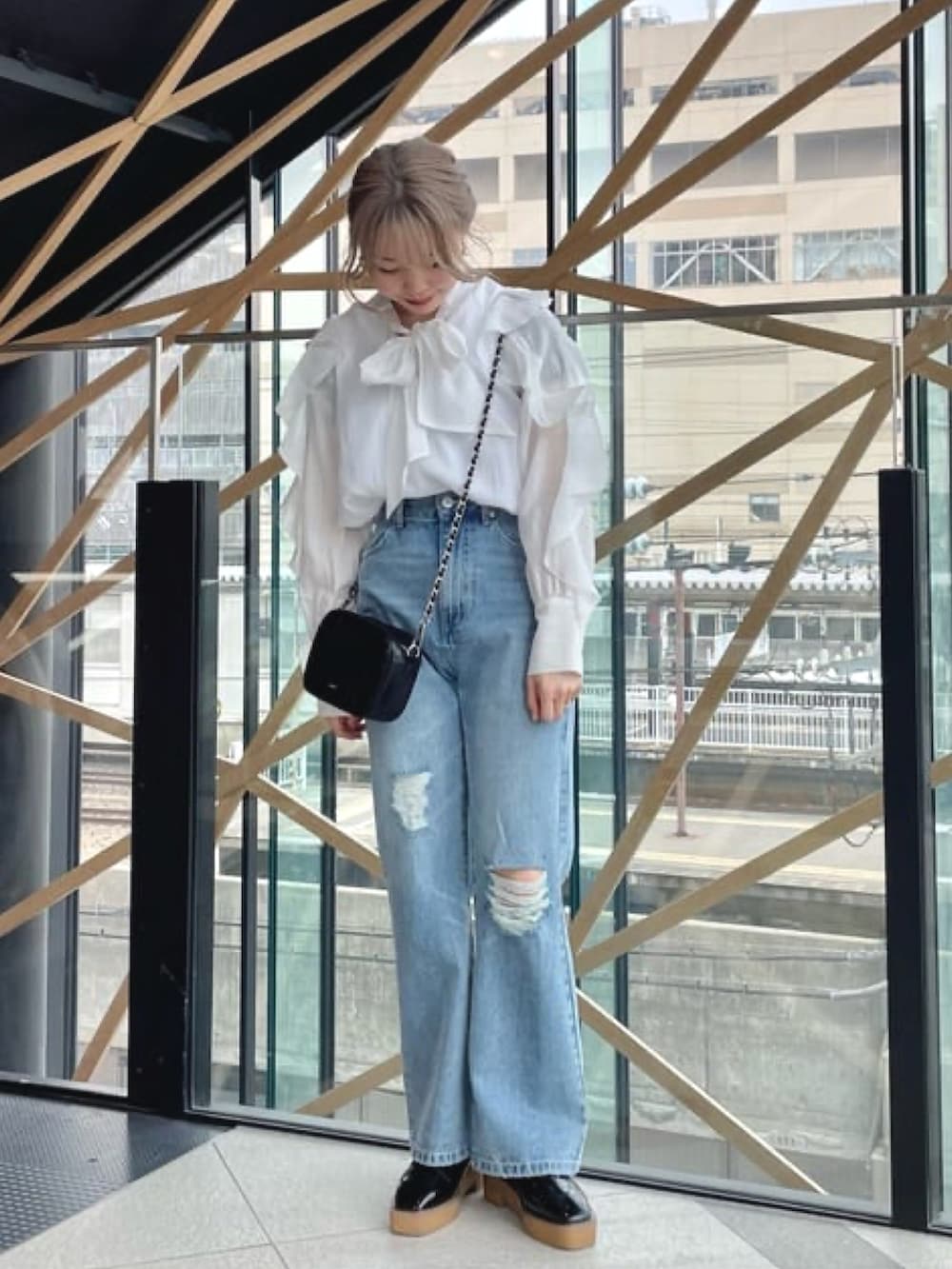 ブラック系のショルダーバッグ、ホワイト系のシャツ/ブラウス、ブルー系のデニムパンツを着用したレディースの冬コーディネートの2枚目の写真