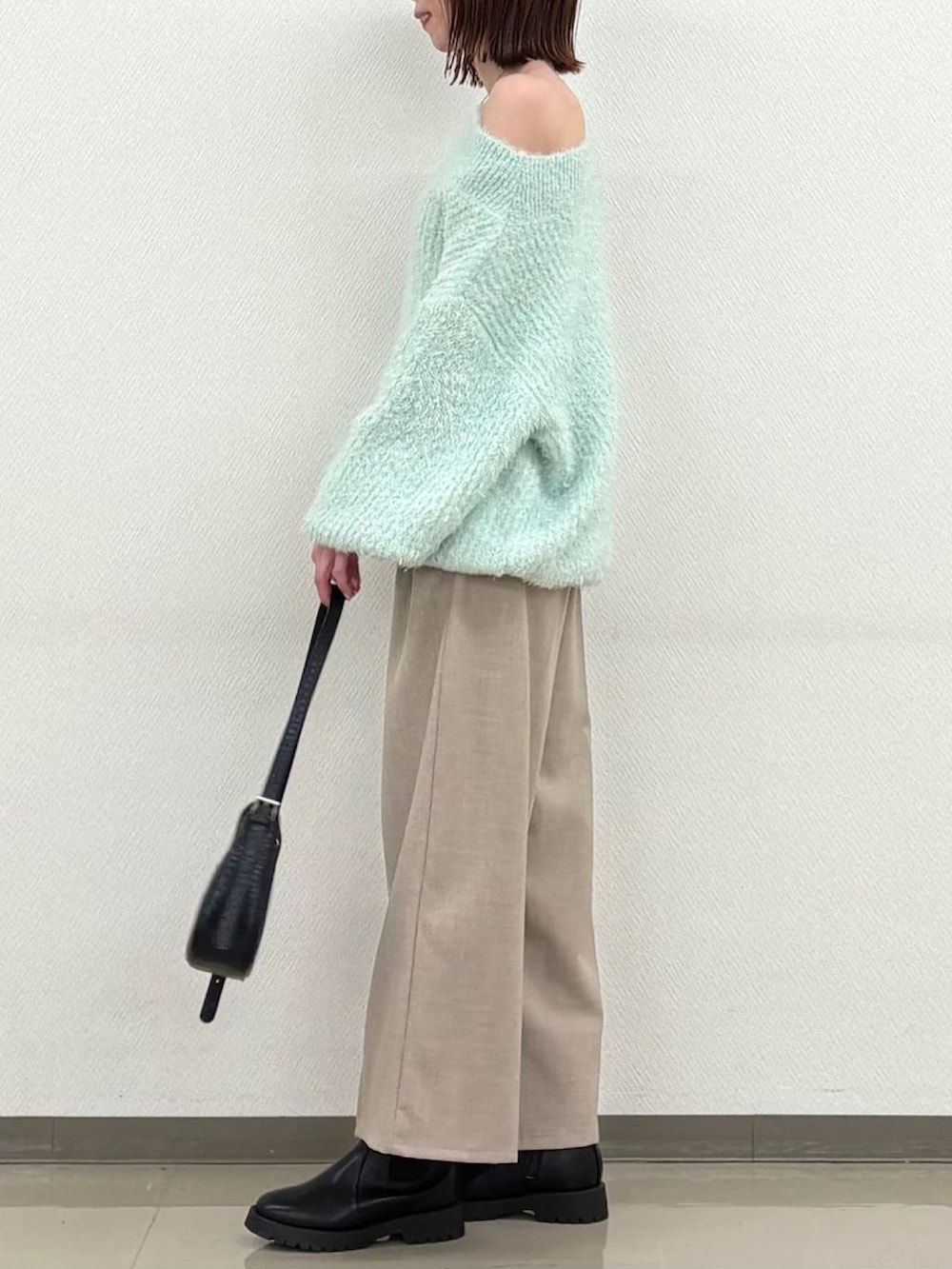 グリーン系のニット/セーターを着用したレディースの冬コーディネートの2枚目の写真