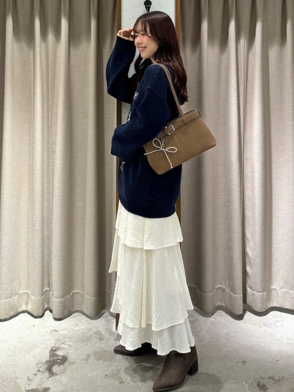 ブルー系のニット/セーター、ホワイト系のスカートを着用したレディースの秋コーディネートの2枚目の写真