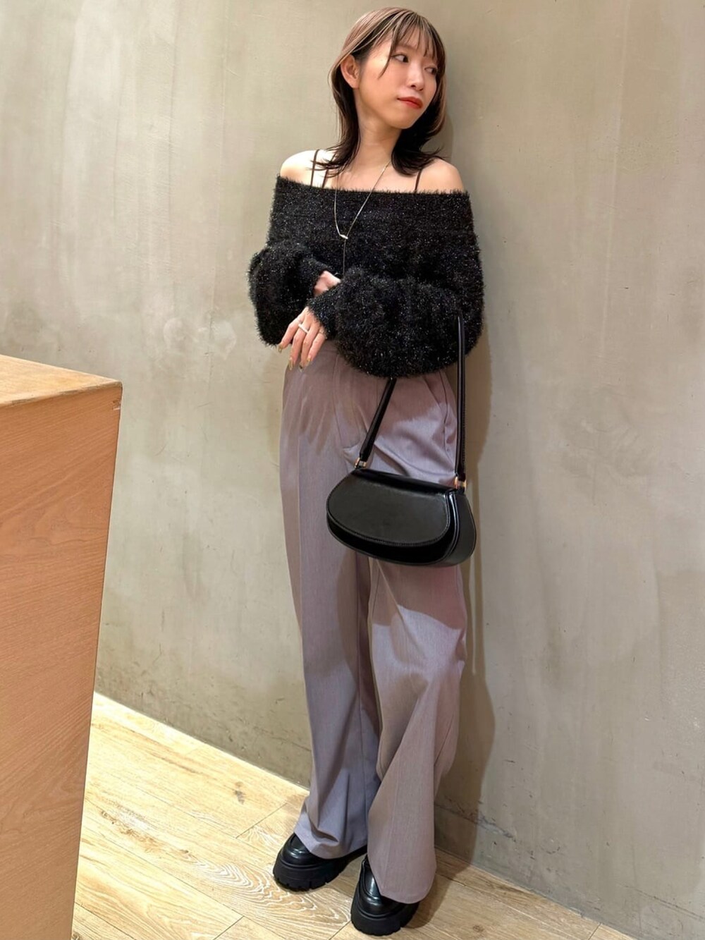 ブラック系のニット/セーター、グレー系のスラックス、ブラウン系のショルダーバッグを着用したレディースの冬コーディネートの2枚目の写真