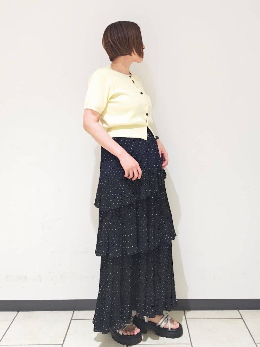 ブラック系のスカート、イエロー系のカーディガン/ボレロ、グレー系のサンダルを着用したレディースの夏コーディネートの2枚目の写真
