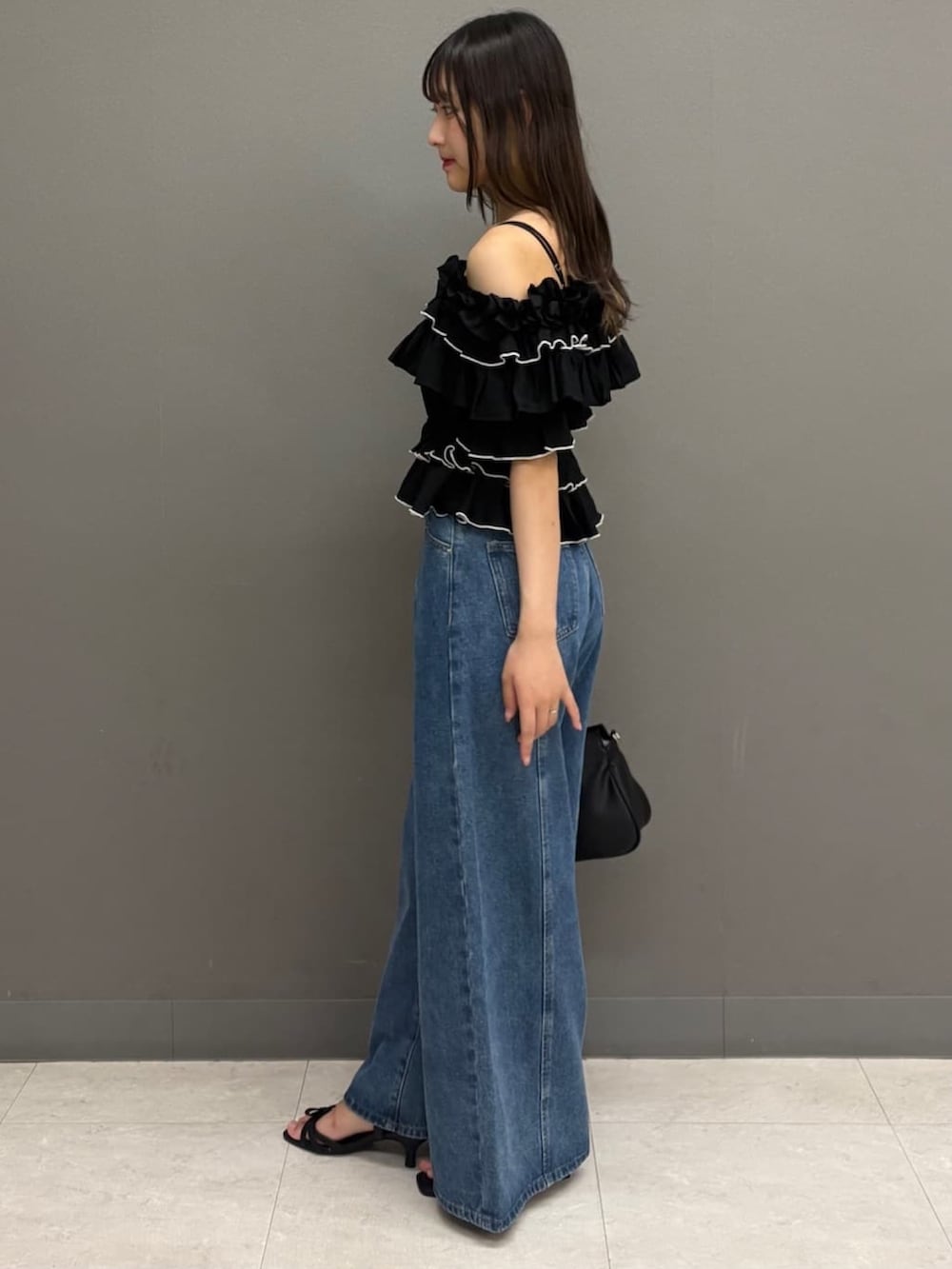 ブルー系のデニムパンツ、ブラック系のサンダル、ブラック系のシャツ/ブラウスを着用したレディースの夏コーディネートの2枚目の写真