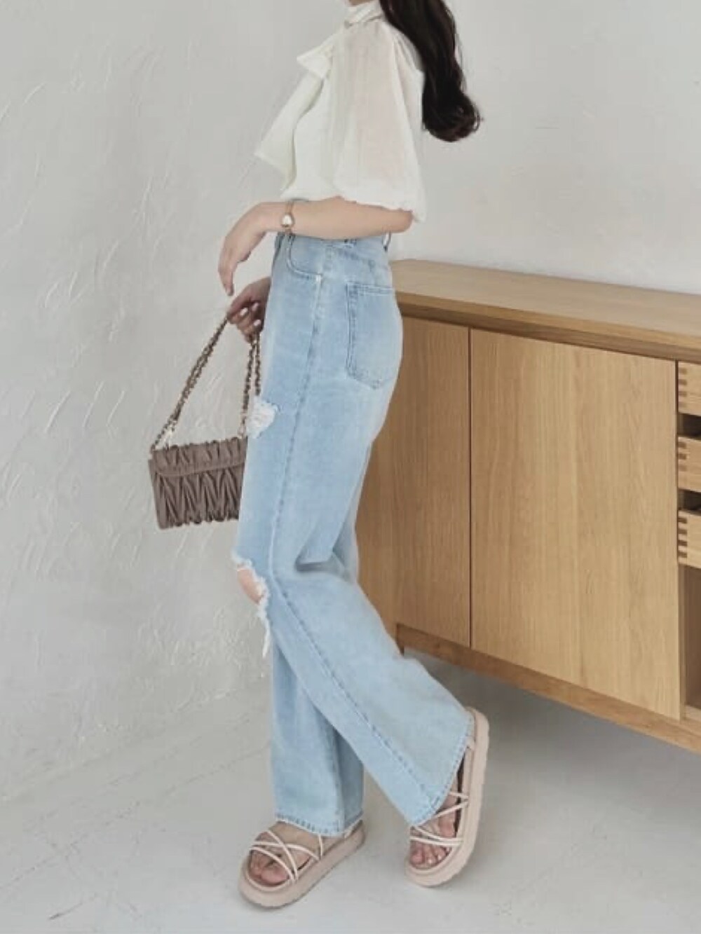 ブルー系のデニムパンツ、ホワイト系のサンダル、ブラウン系のショルダーバッグを着用したレディースの夏コーディネートの2枚目の写真