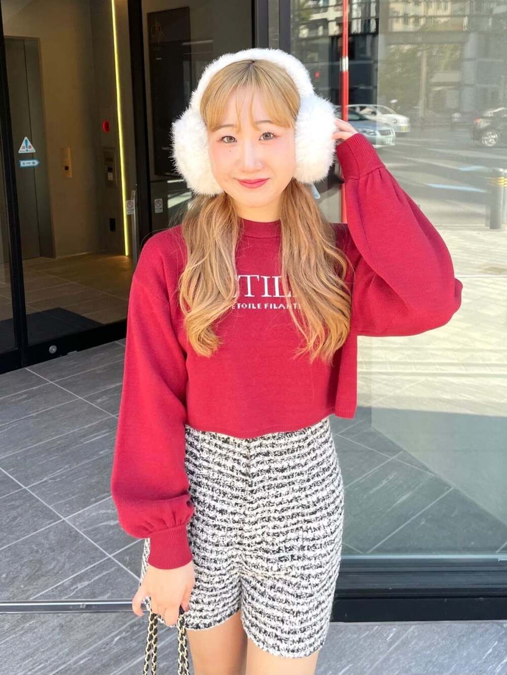 レッド系のニット/セーター、ホワイト系のその他パンツ、ブラック系のブーツを着用したレディースの冬コーディネートの3枚目の写真