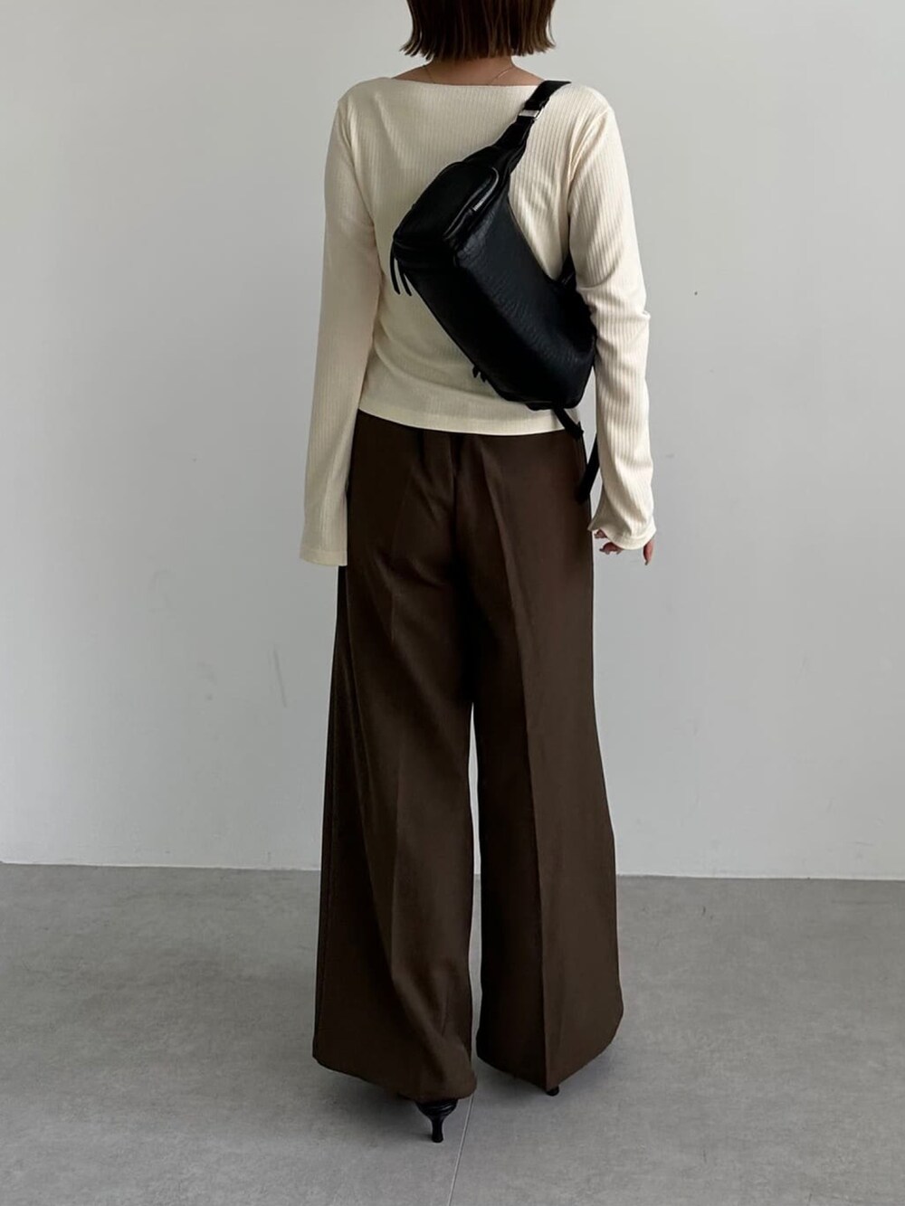ホワイト系のTシャツ/カットソー、ブラウン系のスラックス、ブラック系のパンプスを着用したレディースの秋コーディネートの3枚目の写真