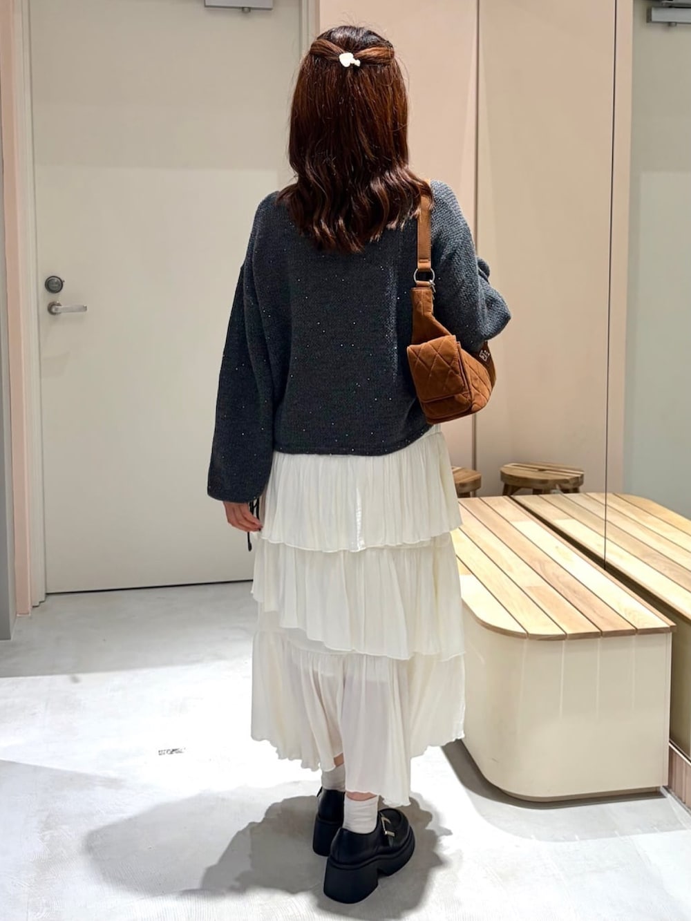 グレー系のニット/セーター、ホワイト系のスカート、ブラウン系のショルダーバッグを着用したレディースの秋コーディネートの3枚目の写真