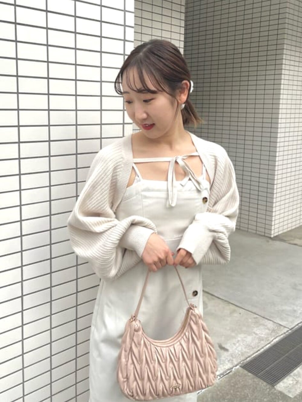 ホワイト系のワンピース、ピンク系のハンドバッグ、ホワイト系のカーディガン/ボレロを着用したレディースの冬コーディネートの4枚目の写真