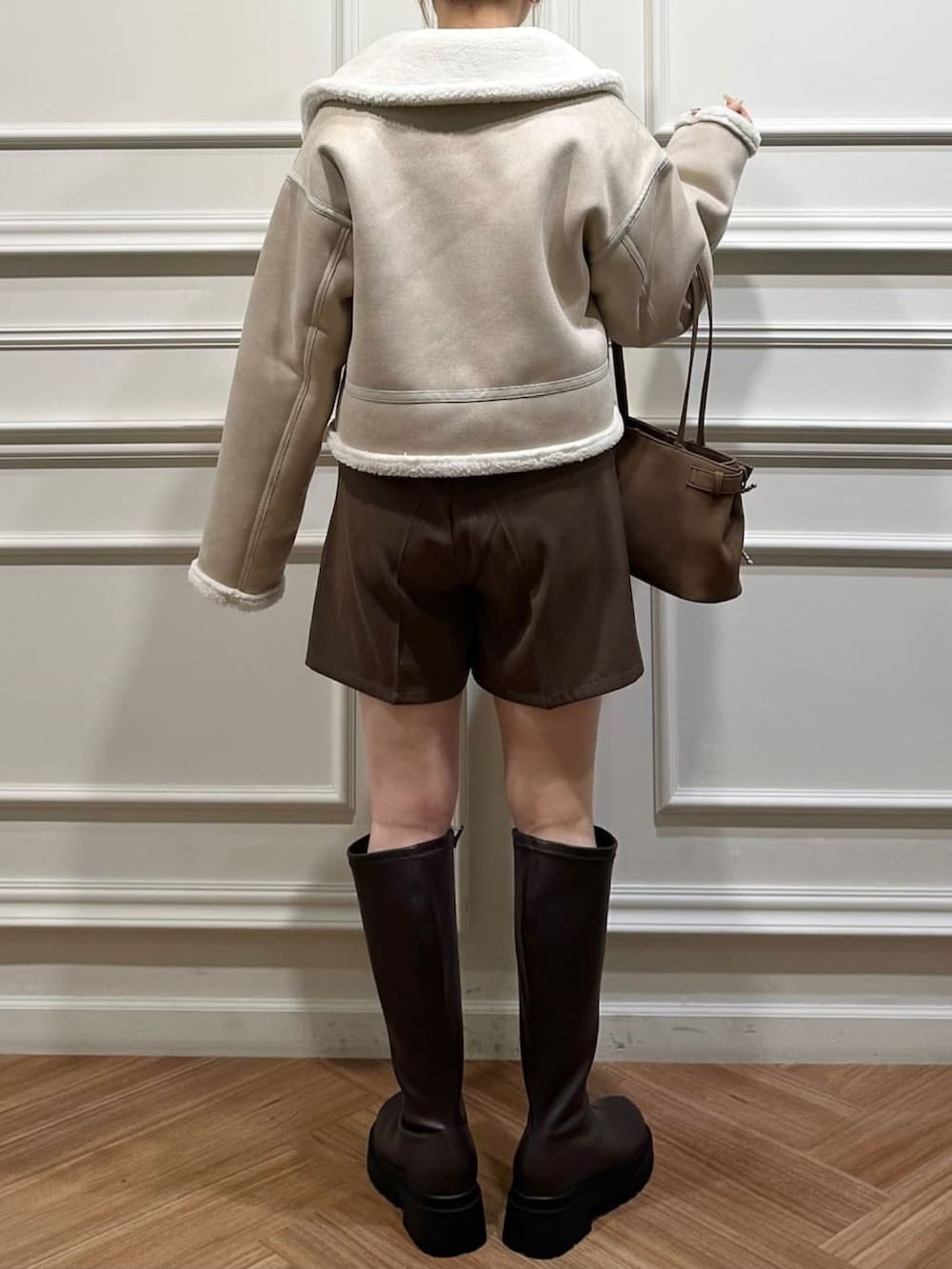 ホワイト系のムートンコートを着用したレディースの秋コーディネートの2枚目の写真