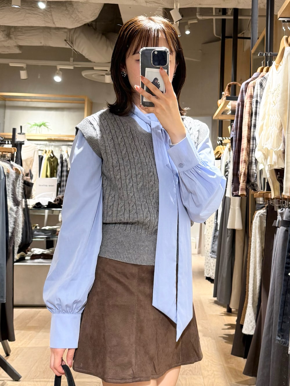 グレー系のニット/セーター、ブラウン系のスカート、ブラック系のショルダーバッグを着用したレディースの秋コーディネートの3枚目の写真