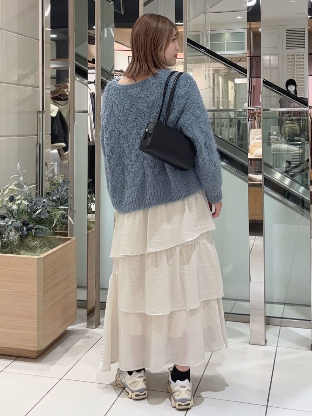 ホワイト系のニット/セーター、ホワイト系のスカート、ブラック系のショルダーバッグを着用したレディースの冬コーディネートの2枚目の写真