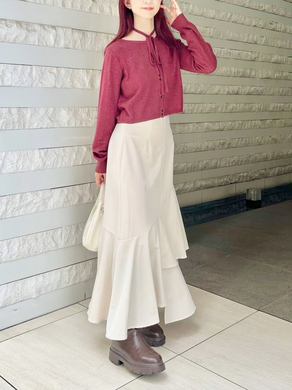 レッド系のカーディガン/ボレロ、ブラック系のスカートを着用したレディースの秋コーディネートの2枚目の写真