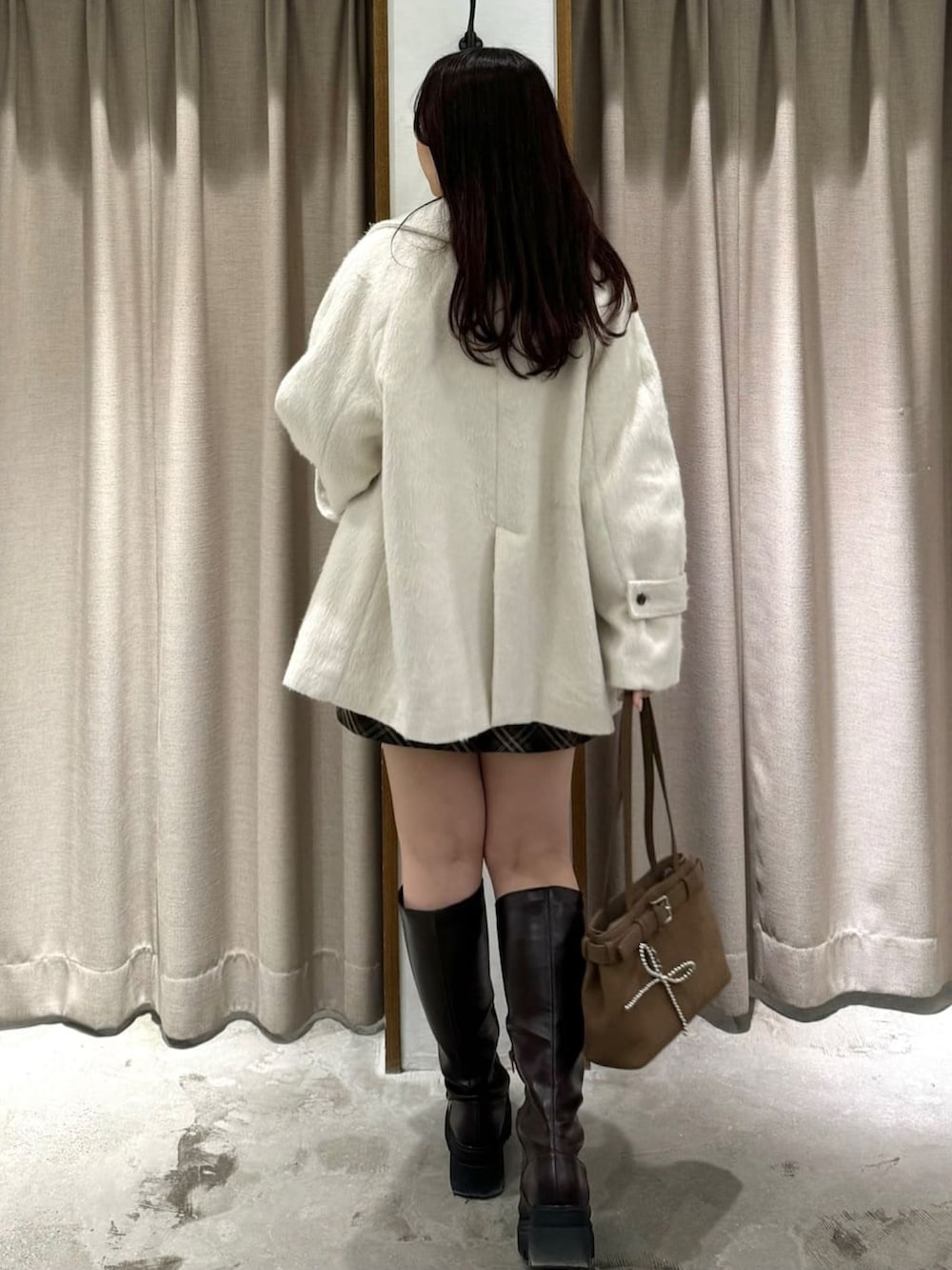 ホワイト系のチェスターコートを着用したレディースの冬コーディネートの3枚目の写真