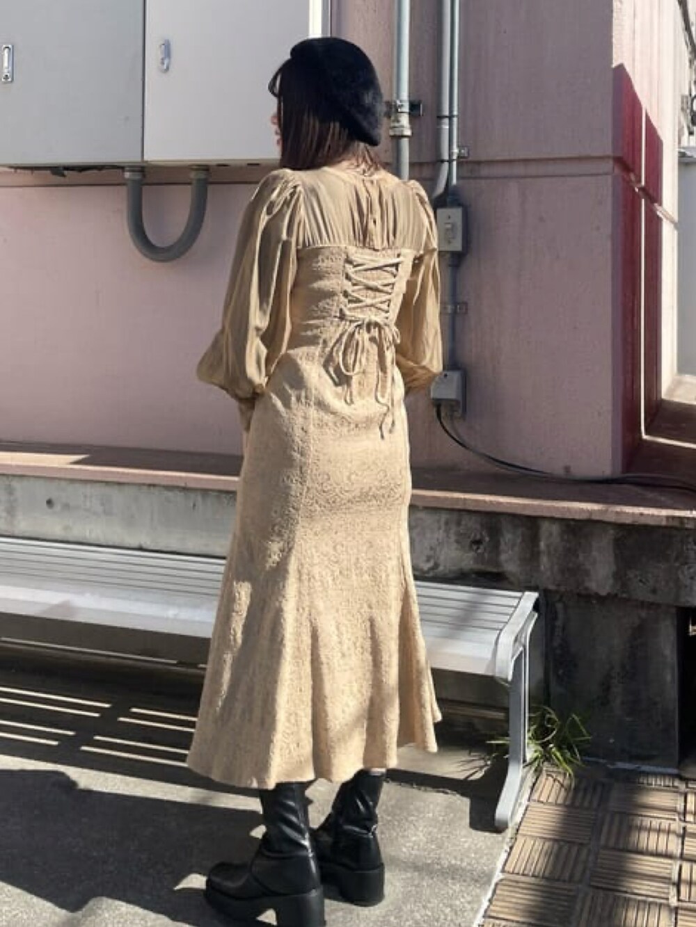 ブラック系のブーツ、ベージュ系のワンピース、ホワイト系のハンドバッグを着用したレディースの冬コーディネートの2枚目の写真