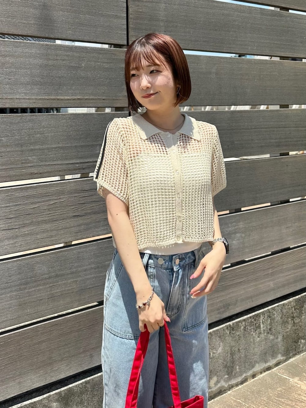 ホワイト系のニット/セーター、ホワイト系のデニムパンツ、レッド系のトートバッグを着用したレディースの夏コーディネートの3枚目の写真