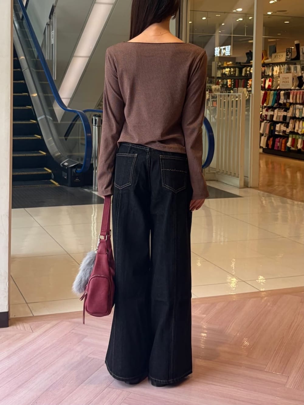 ブラック系のデニムパンツ、レッド系のショルダーバッグ、ブラウン系のTシャツ/カットソーを着用したレディースの秋コーディネートの3枚目の写真
