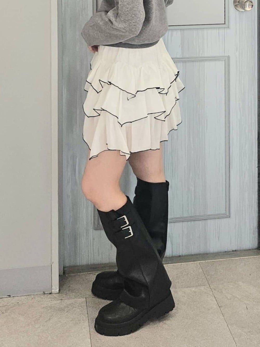 グレー系のニット/セーター、ホワイト系のスカート、ブラック系のボストンバッグを着用したレディースの秋コーディネートの3枚目の写真