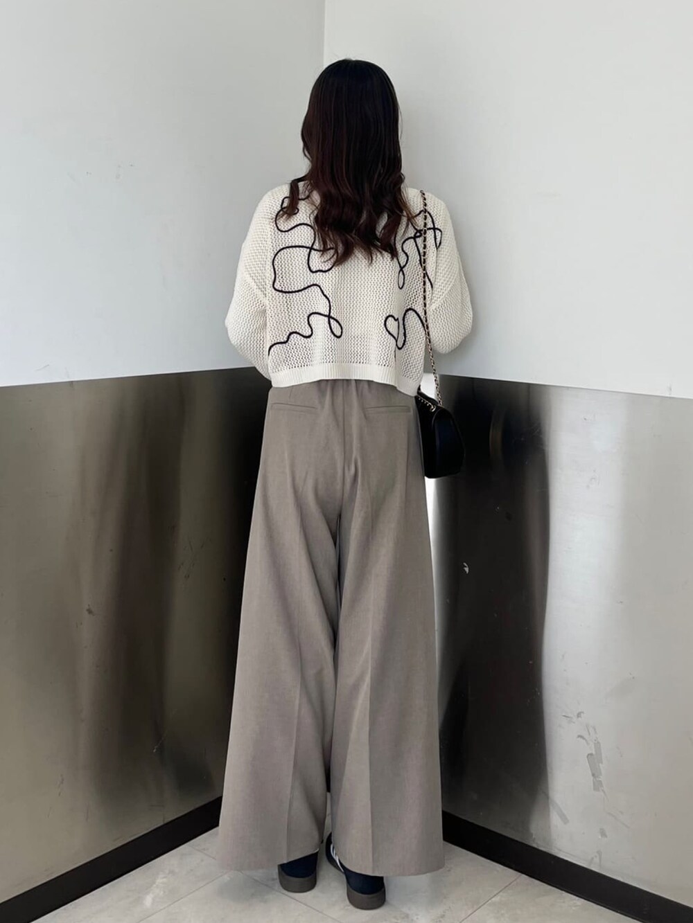 ホワイト系のカーディガン/ボレロ、ブラック系のショルダーバッグ、ブラウン系のスラックスを着用したレディースの春コーディネートの3枚目の写真