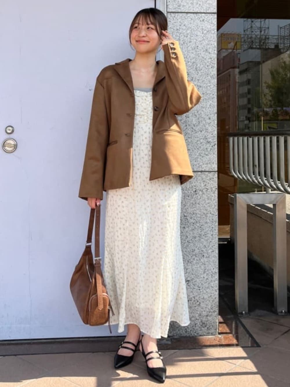 イエロー系のテーラードジャケット、ホワイト系のワンピース、ブラウン系のハンドバッグを着用したレディースの秋コーディネートの2枚目の写真