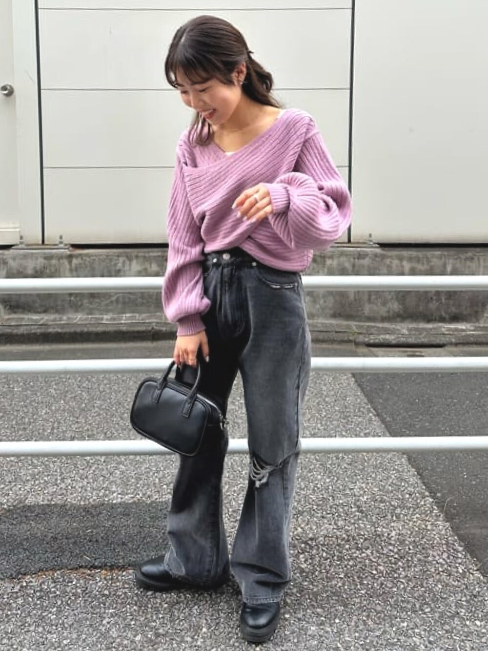 パープル系のニット/セーター、ブラック系のデニムパンツを着用したレディースの冬コーディネートの2枚目の写真