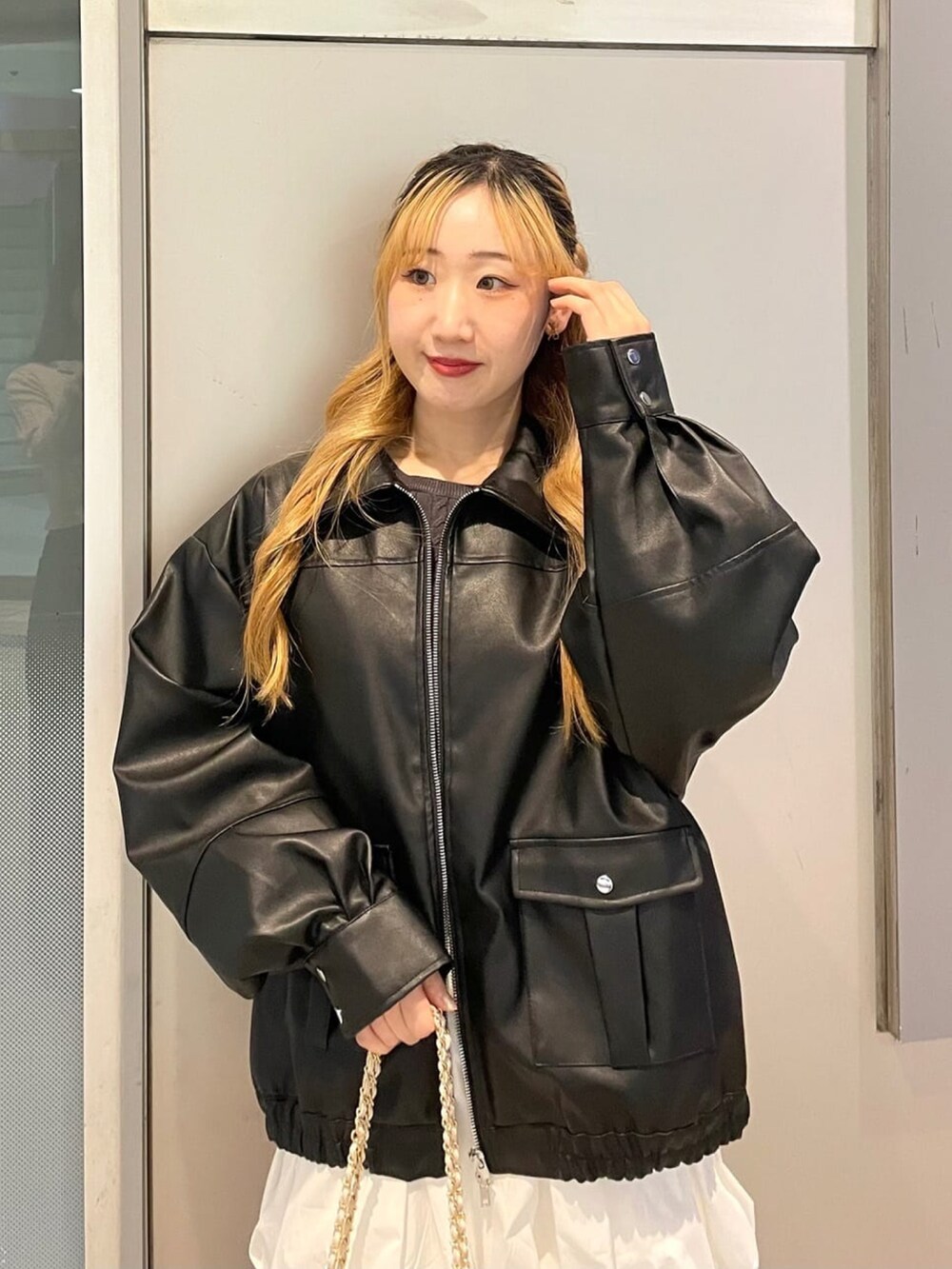 グレー系のニット/セーター、ホワイト系のスカート、ホワイト系のショルダーバッグを着用したレディースの冬コーディネートの3枚目の写真