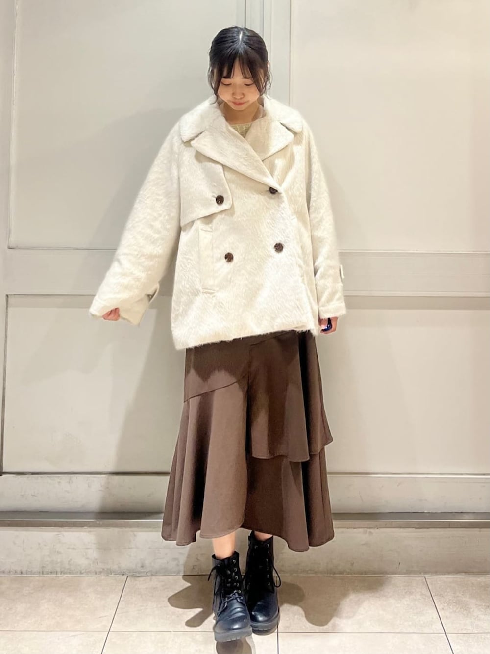 ホワイト系のその他アウター、ホワイト系のニット/セーター、ブラウン系のスカートを着用したレディースの冬コーディネートの2枚目の写真
