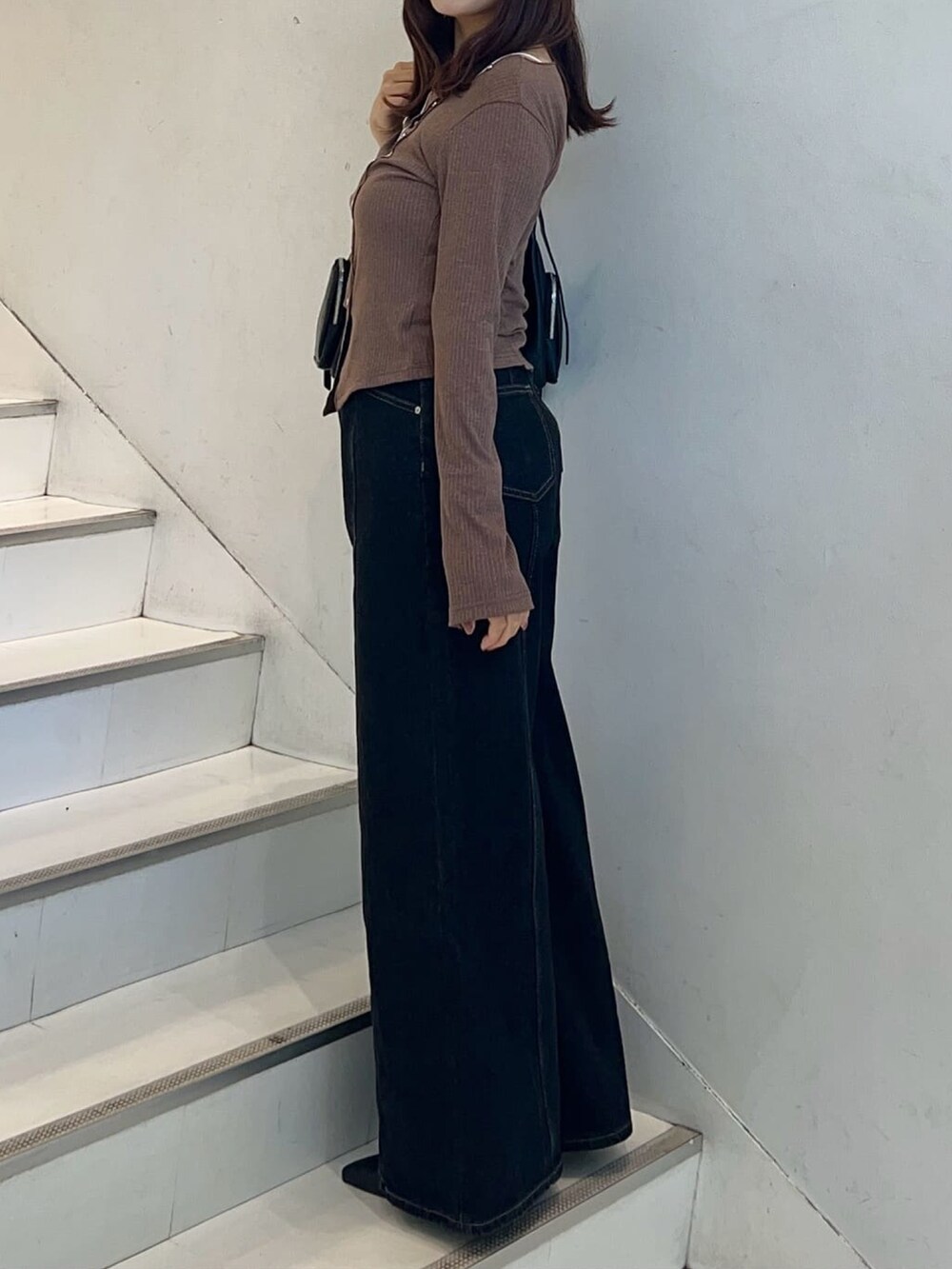 ブラウン系のTシャツ/カットソー、ブラック系のデニムパンツ、ブラック系のハンドバッグを着用したレディースの秋コーディネートの3枚目の写真