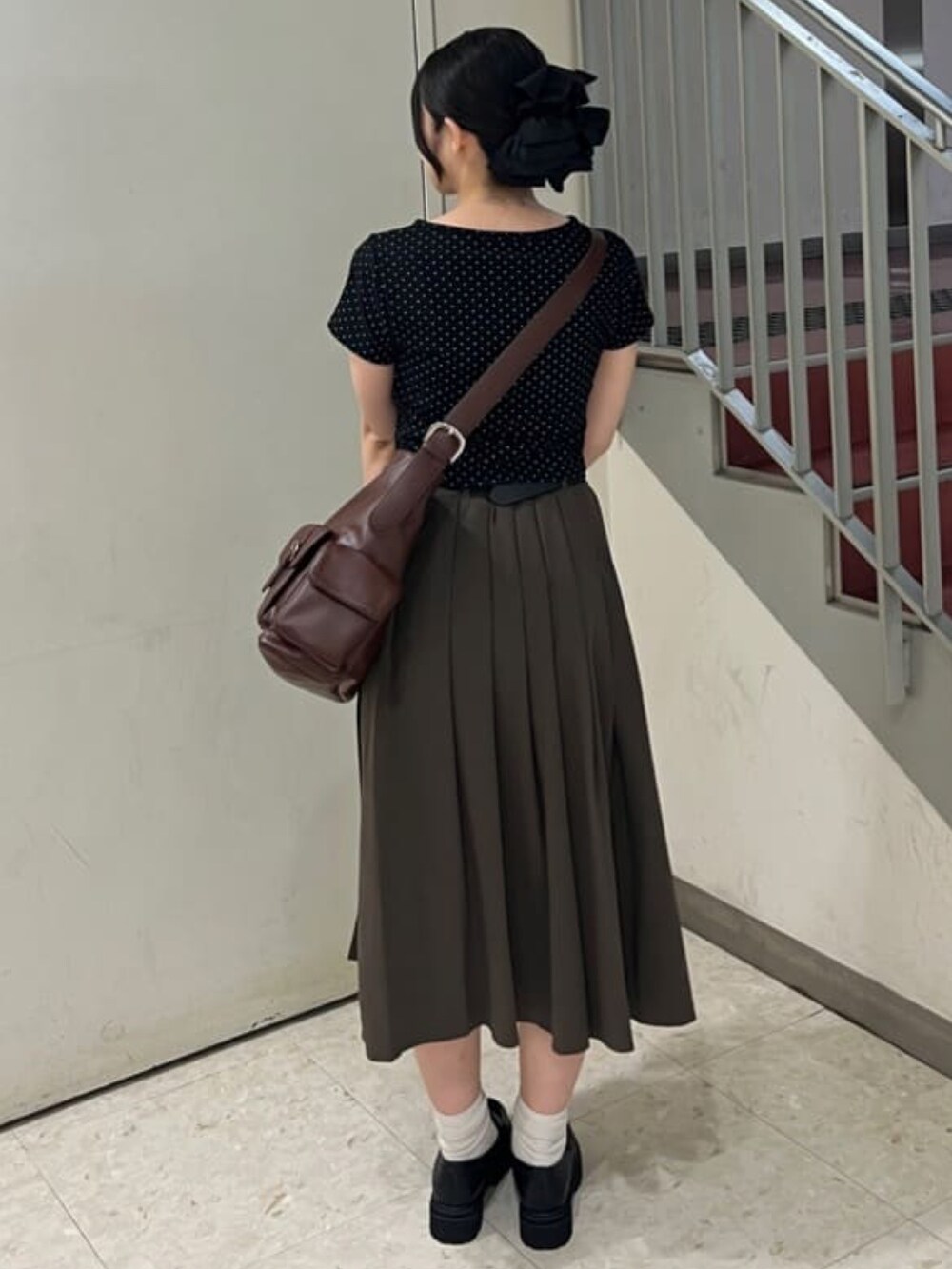 ブラウン系のスカート、ブラック系のショルダーバッグを着用したレディースの夏コーディネートの2枚目の写真