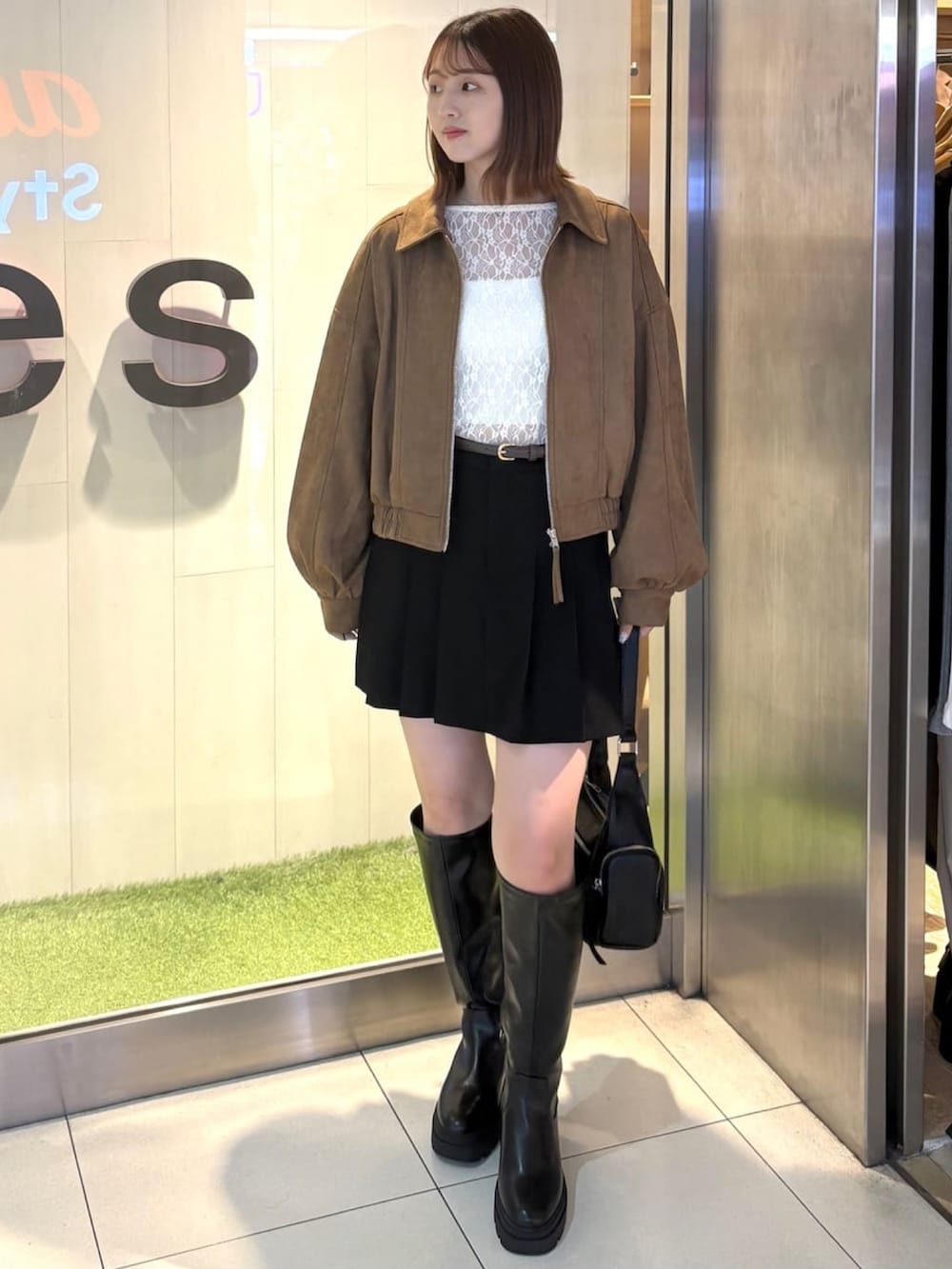 ブラウン系のブルゾン、ブラック系のスカート、ホワイト系のTシャツ/カットソーを着用したレディースの秋コーディネートの2枚目の写真