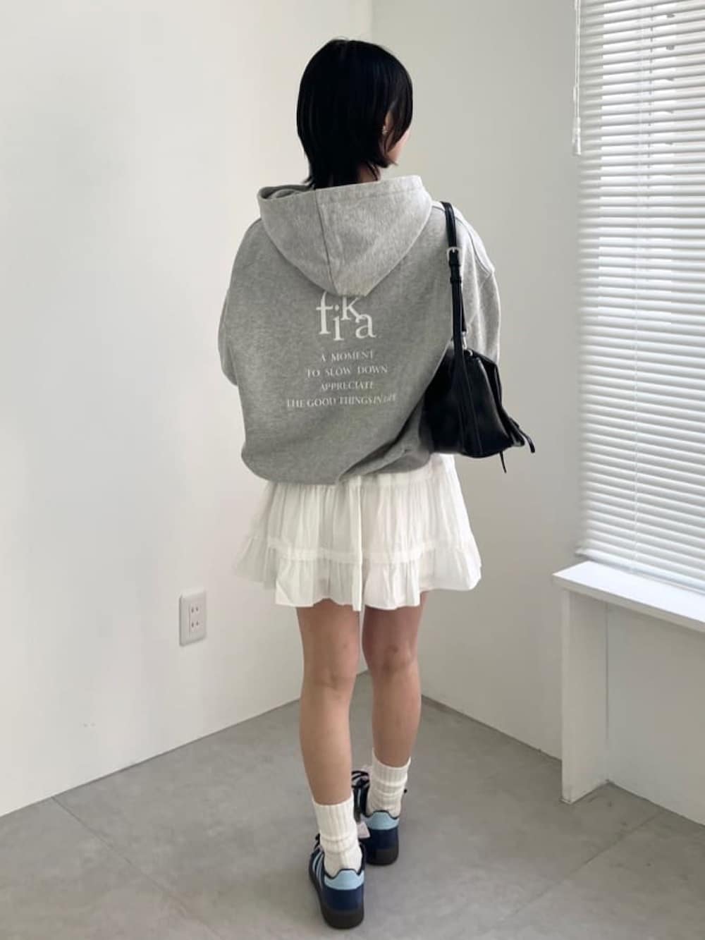 グレー系のパーカー、ホワイト系のスカートを着用したレディースの春コーディネートの3枚目の写真