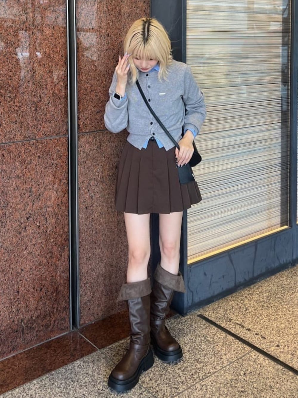 グレー系のカーディガン/ボレロ、ブラウン系のスカート、ブラウン系のブーツを着用したレディースの秋コーディネートの2枚目の写真