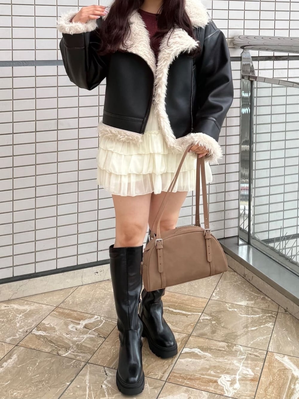 ブラック系のムートンコート、ホワイト系のスカートを着用したレディースの秋コーディネートの3枚目の写真