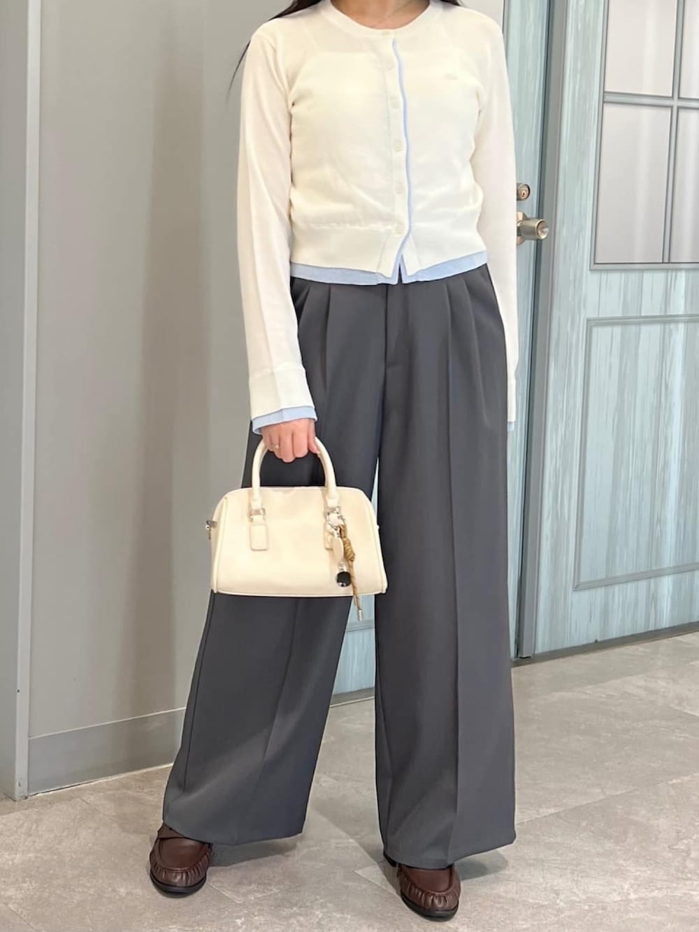 ホワイト系のカーディガン/ボレロ、グレー系のスラックスを着用したレディースの春コーディネートの3枚目の写真