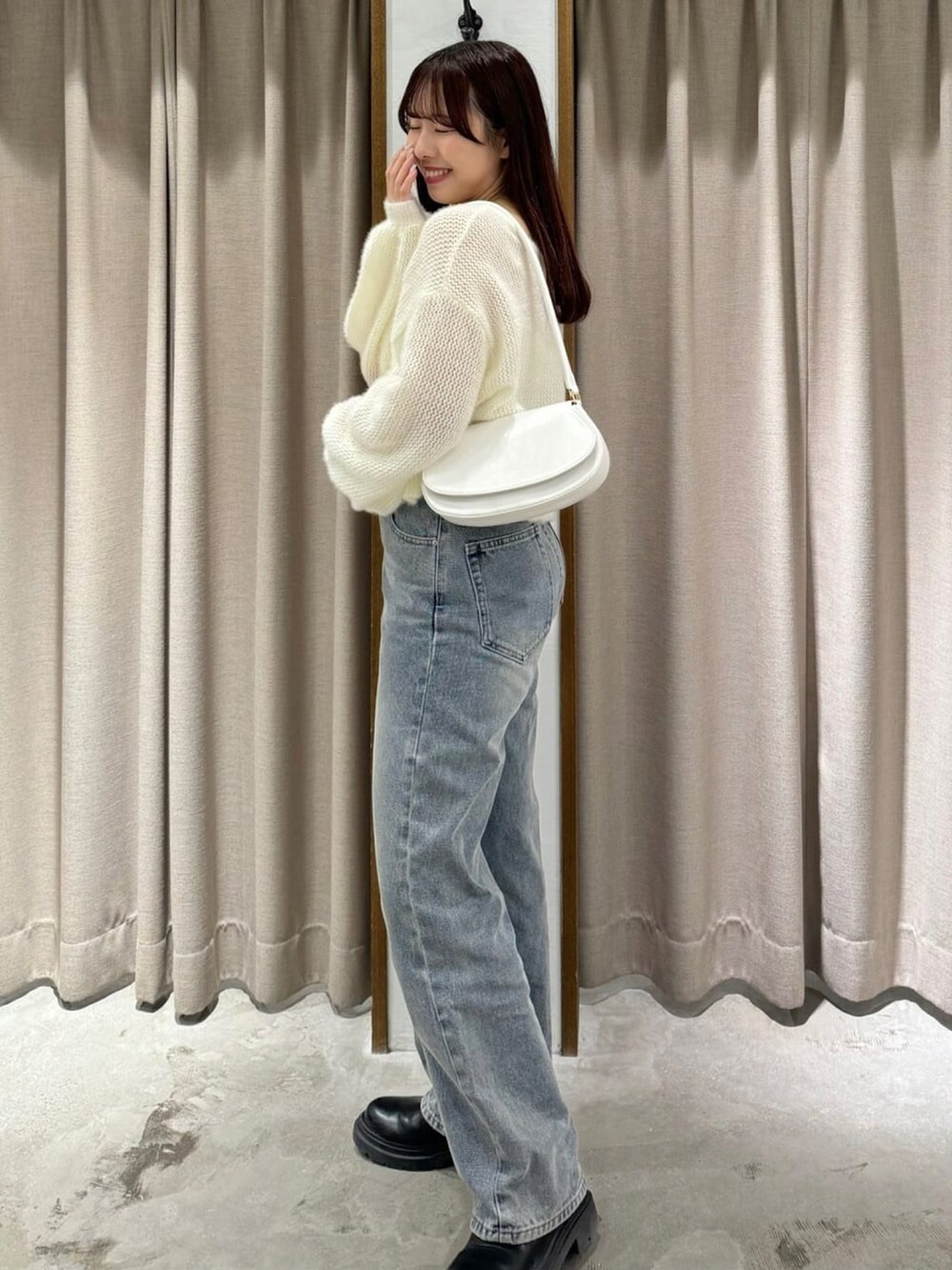 ホワイト系のニット/セーター、ブルー系のデニムパンツ、ホワイト系のショルダーバッグを着用したレディースの冬コーディネートの2枚目の写真