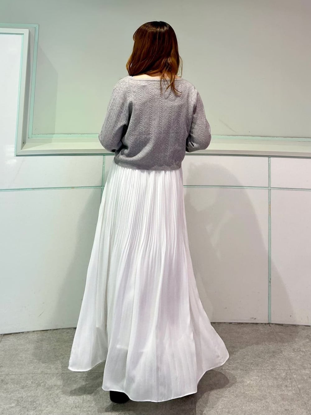 グレー系のカーディガン/ボレロ、ホワイト系のスカートを着用したレディースの秋コーディネートの3枚目の写真